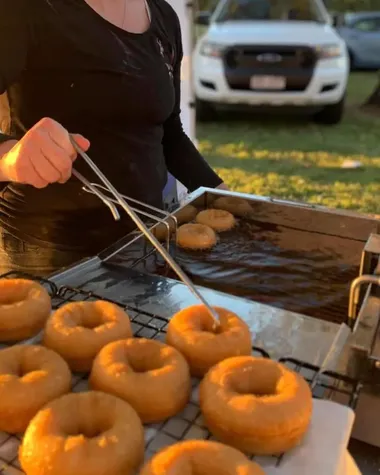 Lifting fresh doughnuts out of the fryer at a market at sunset